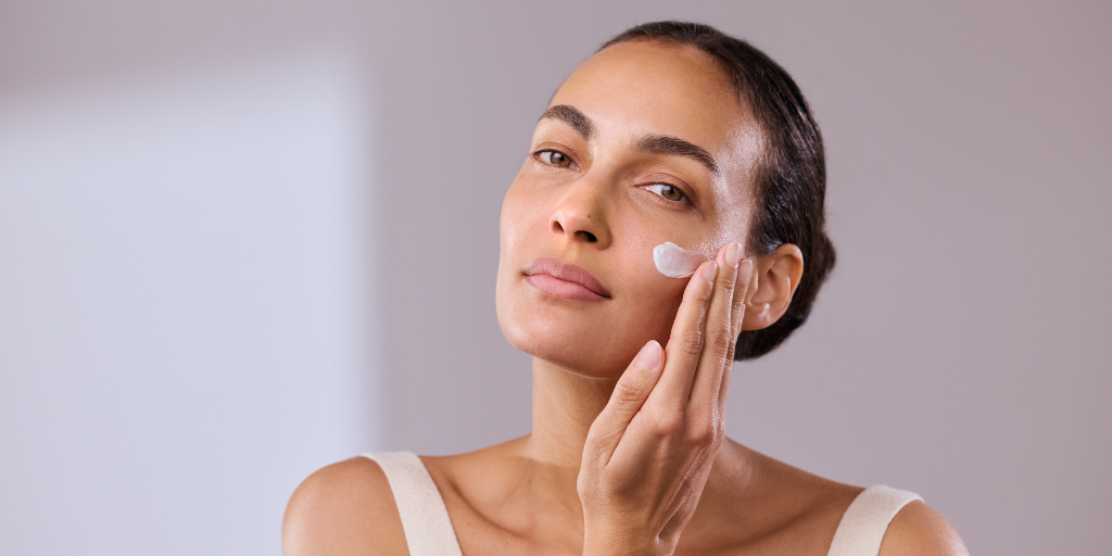 skincare model applying cream on side of face